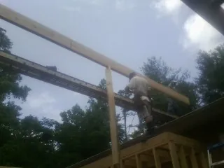 Carpenter setting a ridge beam over a new addition frame — Ice Dam Removal by Roofing Brothers in Saratoga Springs